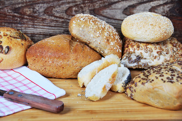 fresh wheat and rye buns with sesame seeds, linseed and pumpkin seeds and sunflower seeds cut with knife