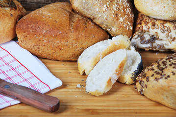 fresh wheat and rye buns with sesame seeds, linseed and pumpkin seeds and sunflower seeds cut with knife