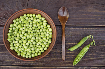 plate with young green peas on a dark wooden background