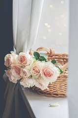 Bouquet of pale pink cream roses in a woven basket on a windowsill. Soft focus. Romance background with copy space.
