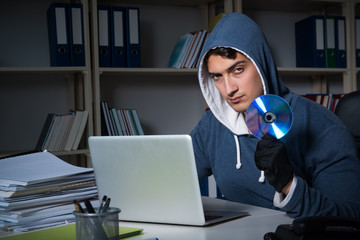 Young hacker hacking into computer at night