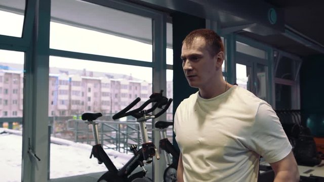 Young guy doing exercises with dumbbells at biceps. Strength and motivation