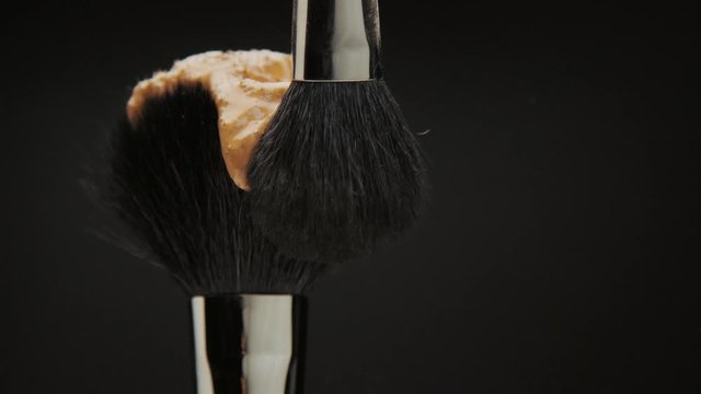 black brush with a liquid foundation and another brush smudge it