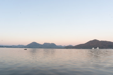 Naklejka na ściany i meble Serene dawn shot of Fateh sagar lake udiapur india. This famous tourist destination of India invites locals and travellers alike to enjoy the blue waters, surrounding hills and great lakeside food