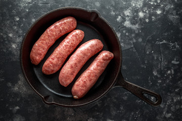 Freshly made raw breed butchers sausages in rustic skillet.