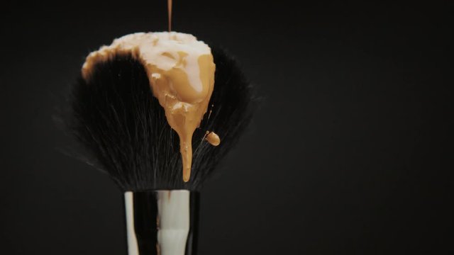 black brush with a liquid foundation pouring on it