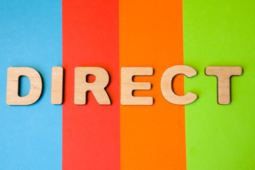 Word Direct of large wooden letters on colored background of 4 colors: blue, orange, red and green. Photo or symbol of the direction, method of computer networking and other concepts