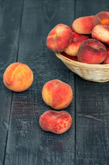 Fototapeta na wymiar ripe peaches in a wicker basket on a dark wooden background