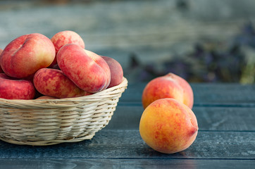 ripe peaches in a wicker basket on a dark wooden background