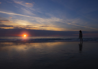 Girl on the beach watching the sunset in the city of San Sebastian
