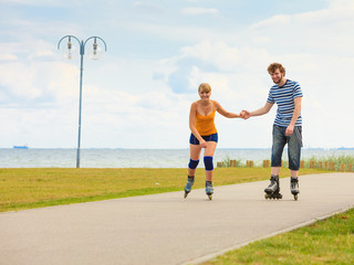 Obraz premium Young couple on roller skates riding outdoors