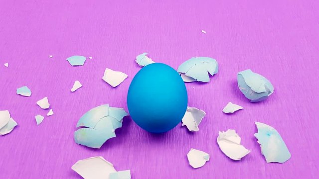 Easter color egg with eggshells on pirple violet background.