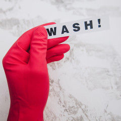 Cleaning office or house concept. Mens hand in red rubber glove holding WASH inscription sign,...