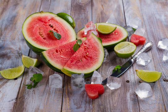 Fresh ripe watermelon slices, lime and mint on wooden table