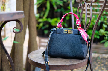 Dark blue Handbag with Pink fabric place on wooden seat of steel chair in the garden