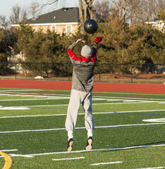 High school athlete throwing medicine ball overhead
