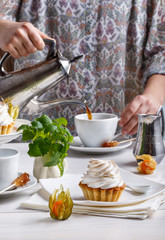 Delicious tartlets with meringue on top. Coffee and cupcakes served on white table.