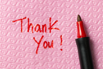 Thank you word written on napkin with red pen