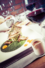 Fried zander, millet with green vegetables, fried boletus with thyme on a green leaf with some egg yolks served in a restaurant
