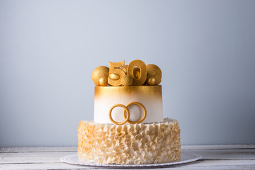 Beautiful cake for the 50th anniversary of the wedding decorated with gold balls and rings. Concept...
