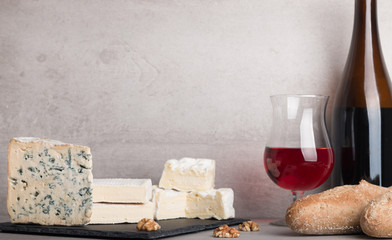  various french cheeses with red wina, grapes,baguette and nuts.