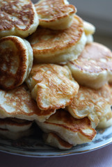 Thick russian pancakes piled on neutral background.