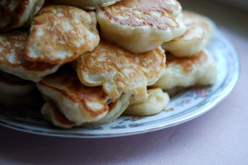 Thick russian pancakes piled on neutral background.