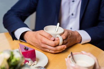 Obraz na płótnie Canvas man drinks coffee with fruit cakes at a cafe