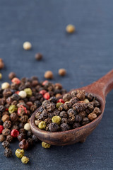 Top view of a wooden spoon full of allspice seeds isolated on dark background, shallow depth of field, front focus