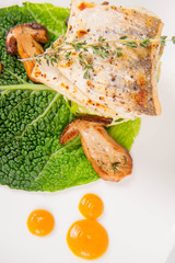 Fried zander, millet with green vegetables, fried boletus with thyme on a green leaf with some egg...