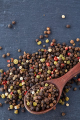 Top view of a wooden spoon full of allspice seeds isolated on dark background, shallow depth of field, front focus