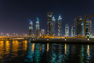Panoramic view of Dubai Business bay at night, reflection of the lights in Dubai Creek. Dubai, UAE