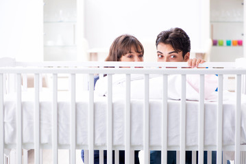 Happy young family at baby bed cot