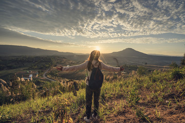 Cheering young woman traveler looking at sunrise