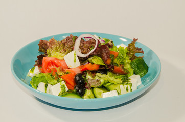 Greek salad with vegetables cheese and greens on a white background