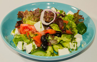 Greek salad with vegetables cheese and greens on a white background