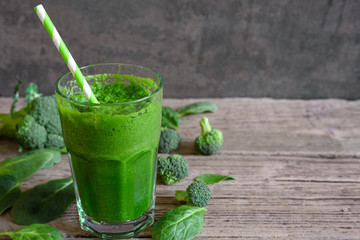 green healthy smoothie in a glass with broccoli, spinach and chia seeds with a straw