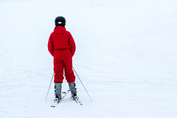 Fototapeta na wymiar Young girl in red suit on ski resort
