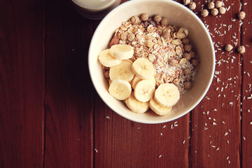 Healthy breakfast. Copy space. Granola bowl with banana, raisins and nuts and on the wooden background. Close up photo. Top view. Sweet vegan dish. Morning oatmeal closeup.