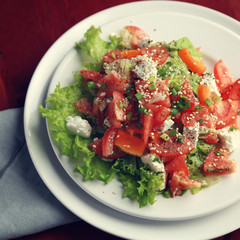 Colorful salad with vegetables and cottage cheese. Top view. European cuisine. Close up. Lacto vegetarian dish. Toned photo. Tomatoes, celery, leafy greens and sesame seeds.