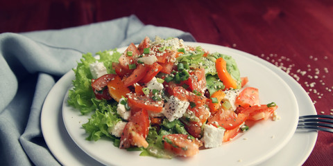 Salad with vegetables and cottage cheese. Close up. European cuisine. Tomatoes, celery, leafy greens and sesame seeds. Lacto vegetarian dish.