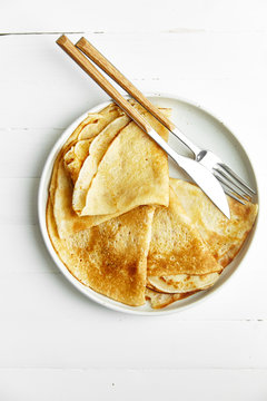 Overhead image of french crepes in white plate on wooden table