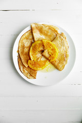 Overhead image of pancakes with orange confiture in white plate on wooden table