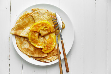 Overhead image of pancakes with orange confitur in white plate on wooden table with space left for text