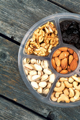 Mixture of fruits and nuts on a tray. Wooden background.