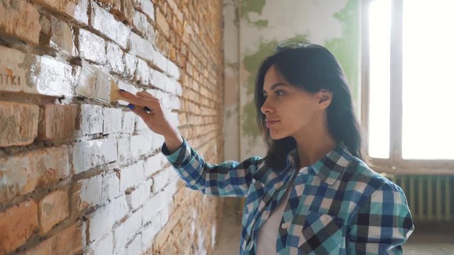 Beautiful young woman doing wall painting.