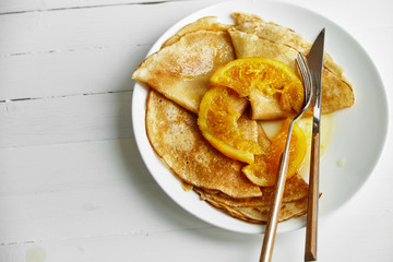 Overhead image of pancakes in white plate on wooden table