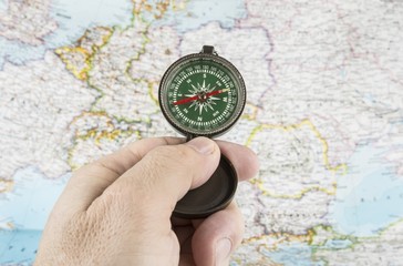 Compass in the hand with map in the background