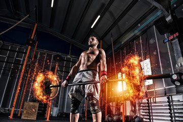 Fototapeta na wymiar Athletic man works out at the gym with a fiery barbell