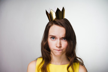 sad young girl in a yellow dress and with a golden crown on her head waiting for a world women's day